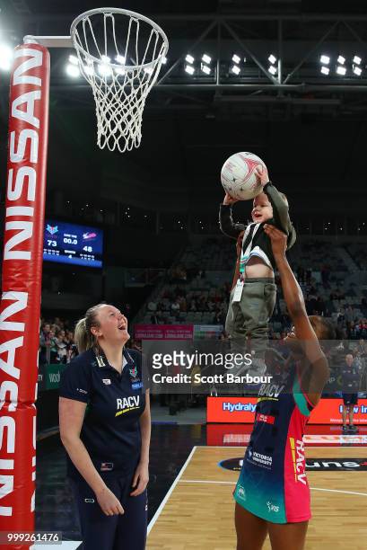 Kadie-Ann Dehaney of the Vixens holds Jacob Ingles up so he can shoot the ball as Emma Ryde looks on after the round 11 Super Netball match between...