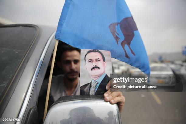 Yemeni man holds a poster depicting former president Ali Abdullah Saleh, ahead of an anniversary celebration of Saleh's party, General People's...