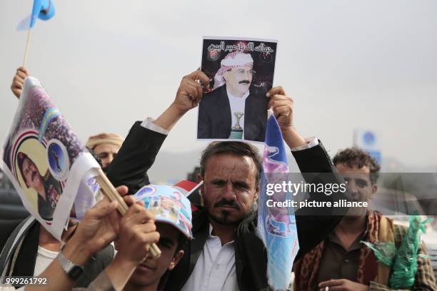 Yemeni man holds a poster depicting former president Ali Abdullah Saleh, ahead of an anniversary celebration of Saleh's party, General People's...