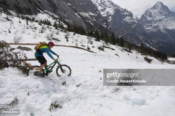 mountainbiker absteigt lawinenschnee über grindelwald - eskapismus stock-fotos und bilder