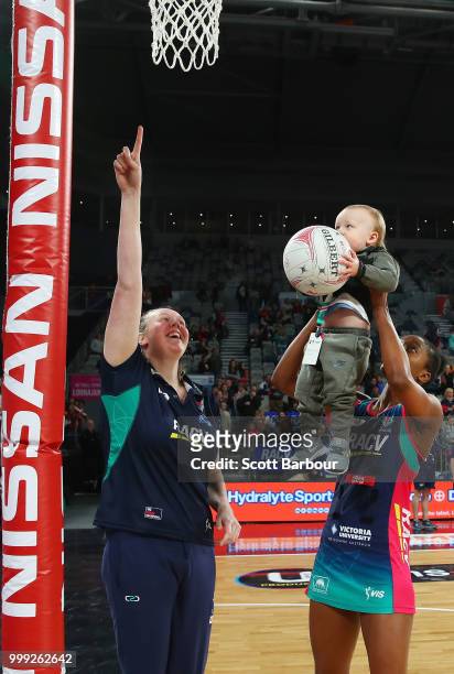 Kadie-Ann Dehaney of the Vixens holds Jacob Ingles up so he can shoot the ball as Emma Ryde looks on after the round 11 Super Netball match between...