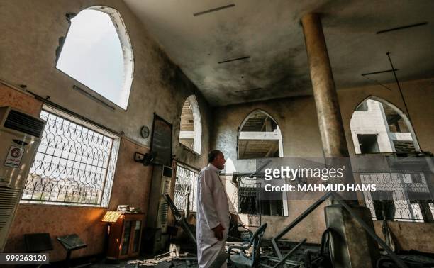 Palestinian men inspect damages to a mosque that was hit by Israeli air strikes the day before in Gaza City on July 15, 2018. - Israel's military...