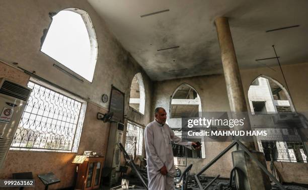 Palestinian men inspect damages to a mosque that was hit by Israeli air strikes the day before in Gaza City on July 15, 2018. - Israel's military...