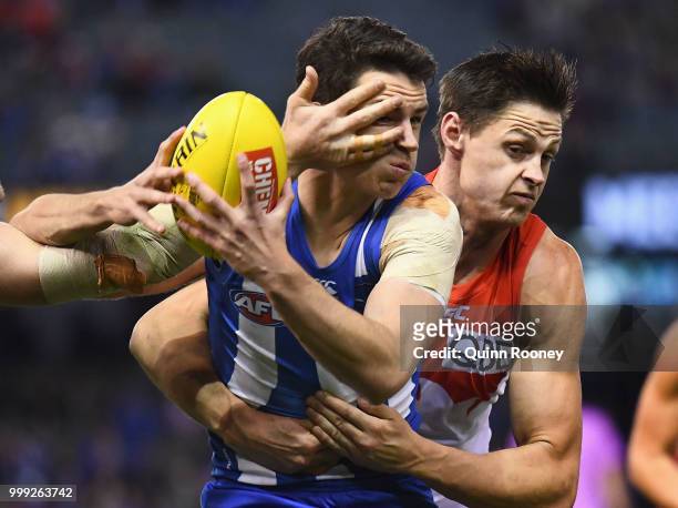 Luke Davies-Uniacke of the Kangaroos is tackled by Callum Sinclair of the Swans during the round 17 AFL match between the North Melbourne Kangaroos...