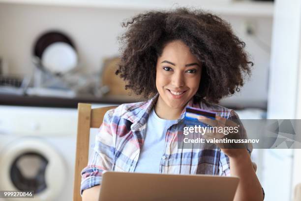 femme souriante avec cedit carte et l’ordinateur portable à la maison - utiliser lordinateur photos et images de collection