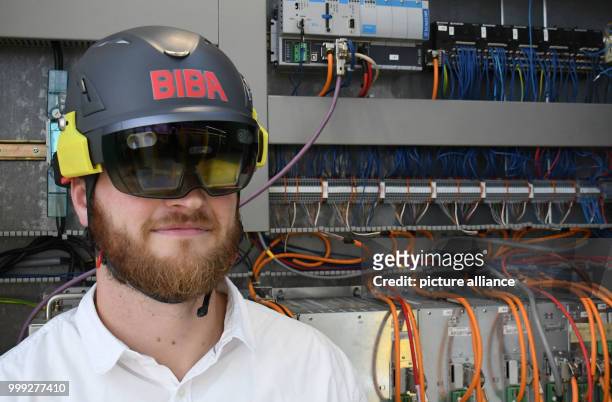 Moritz Quandt, research assistant at the Institut für Produktion und Logistik GmbH at the University of Bremen wears data glasses while standing in...