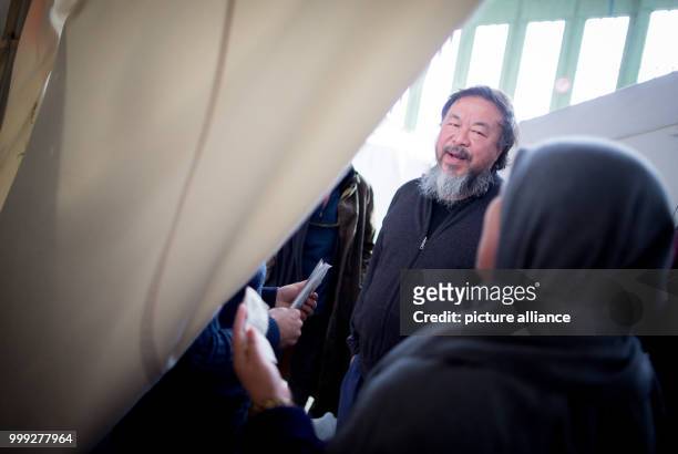 The Chinese artist Ai Weiwei speaks with an Iraqi woman at a hangar of the refugee emergency shelter at the former Tempelhof Airport in Berlin,...