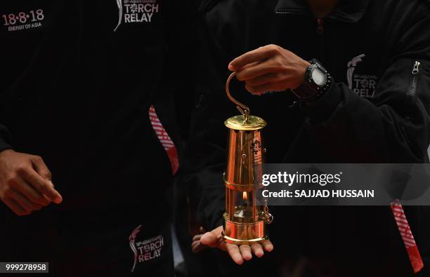 Officials hold the flame during the 2018 Asian Games torch relay in New Delhi on July 15, 2018. - Indonesia will host the 2018 Asian Games from...