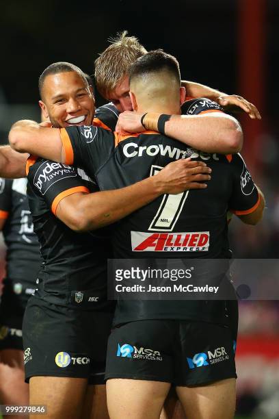 Moses Mbye celebrates with Luke Brooks of the Tigers after winning the round 18 NRL match between the St George Illawarra Dragons and the Wests...