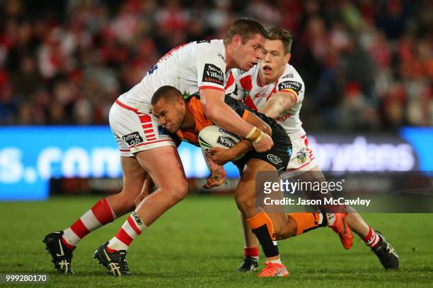 Moses Mbye of the Tigers is tackled by Jeremy Latimore and Cameron McInnes of the Dragons during the round 18 NRL match between the St George...