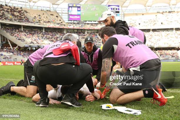 Robbie Gray of the Power is attended to by medical staff after being tackled by Ryan Nyhuis of the Dockers during the round 17 AFL match between the...