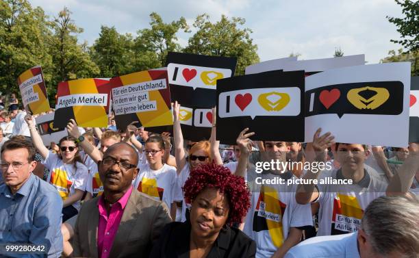 Supporters of the German Christian Democratic Union hold up posters with expressions of sympathy for the German Chancellor Merkel in during the...