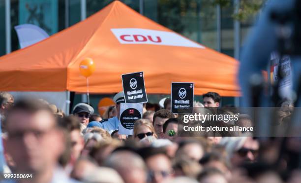 Protestors hold up signs saying 'Multikulti hat fertig' in front of a German Christian Democratic Union's tent in Muenster, Germany, 22 August 2017....