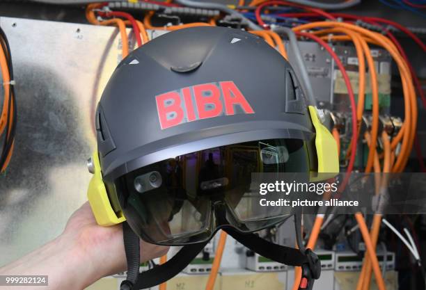 An employee of the Institut für Produktion und Logistik GmbH at the University of Bremen holding the data glasses in front of a switch box in Bremen,...