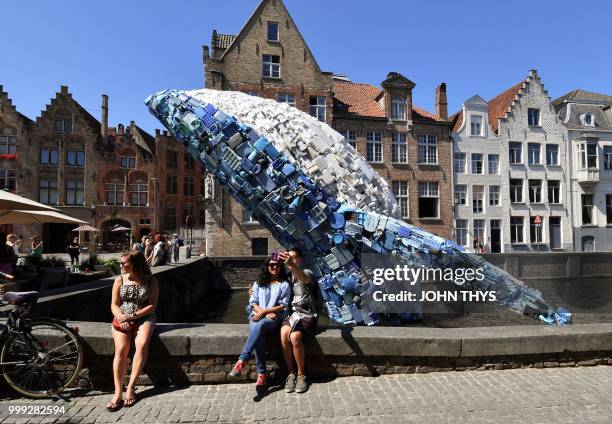 Tourists pose for a selfie picture with a 12-metre installation depicting a whale, made up of five tons of plastic waste pulled out of the Pacific...