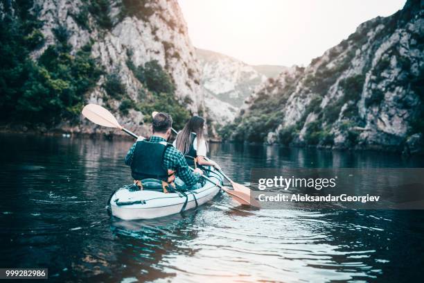 young couple oaring towards canyon's end in kayak - aleksandar georgiev stock pictures, royalty-free photos & images