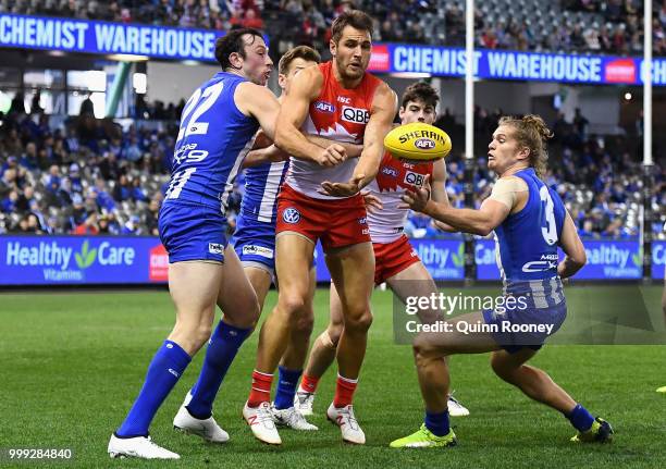 Josh Kennedy of the Swans handballs whilst being tackled by Todd Goldstein of the Kangaroos during the round 17 AFL match between the North Melbourne...
