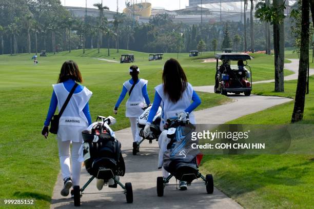 Indonesian caddies make their way to the clubhouse at the Pondok Indah Golf Course in Jakarta on July 15 which will be the venue of the golf...