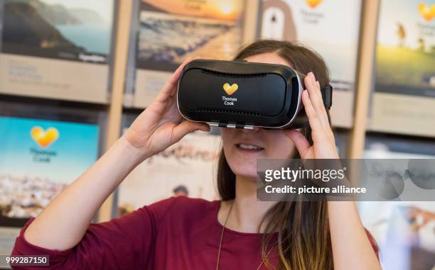 Picture of a woman looking at potential travel destinations through virtual reality headsets in a travel agency in Hanover, Germany, 16 August 2017....