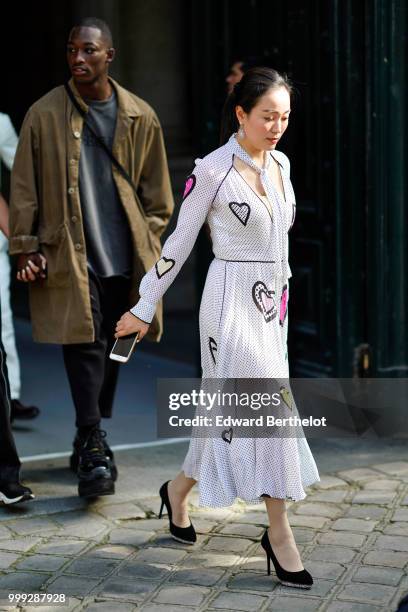 Guest wears a white pleated dress with printed mini dots and hearts, outside Dior, during Paris Fashion Week - Menswear Spring-Summer 2019, on June...