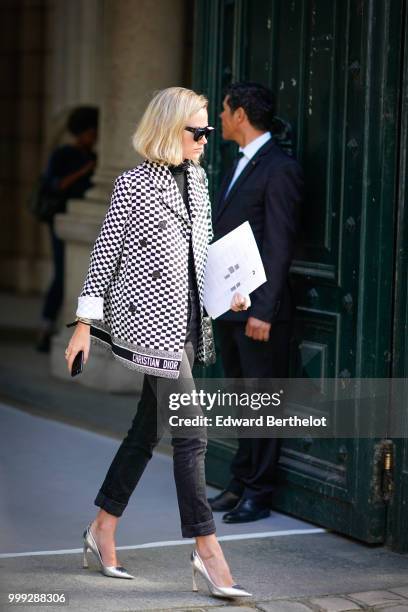 Guest wears a black and white checked printed Christian Dior blazer jacket, cropped black pants, silver heels shoes, sunglasses, outside Dior, during...