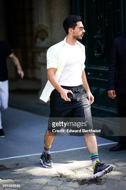 Guest wears a white shirt, a wite top, black shorts, sneakers, outside Dior, during Paris Fashion Week - Menswear Spring-Summer 2019, on June 23,...