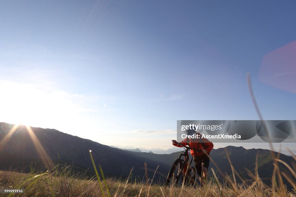 Mountainbiker schiebt Fahrrad bergauf über Bergen