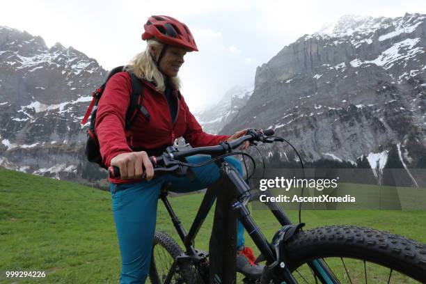 vrouw rijdt elektrische fiets in de zwitserse alpen - escapisme stockfoto's en -beelden