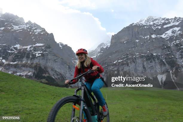 vrouw rijdt elektrische fiets in de zwitserse alpen - escapisme stockfoto's en -beelden
