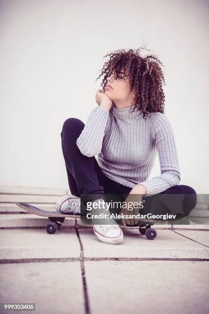 entzückende weibliche auf skateboard sitzen und träumen - aleksandar georgiev stock-fotos und bilder