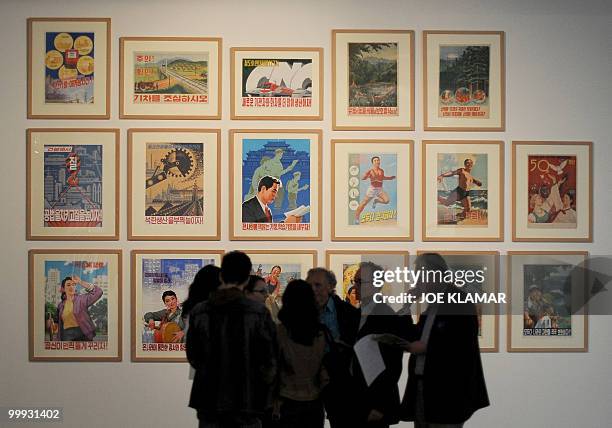 Group of visitors speak in front of a serie of posters during the opening of Democratic People's republic of North Korean state art exhibition...