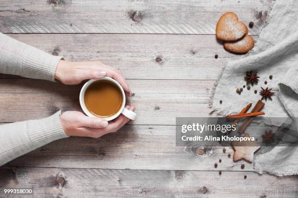 woman holding the cup of beverage. wooden table decorated with c - alina stockfoto's en -beelden