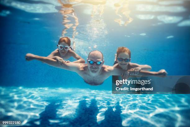 père et fils, jouant sous l’eau dans la piscine - piscine de complexe balnéaire photos et images de collection