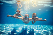 Father and sons playing underwater in resort pool