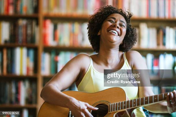 glückliche frau spielt gitarre und singt - soul music stock-fotos und bilder