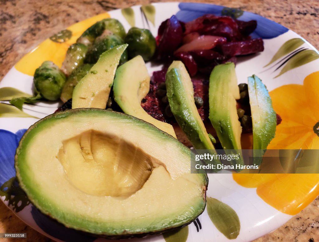 Half an avocado and some slices on a dinner plate