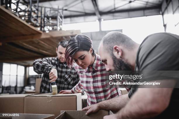 team of factory workers packing merchandise in boxes for shipping - tape dispenser stock pictures, royalty-free photos & images