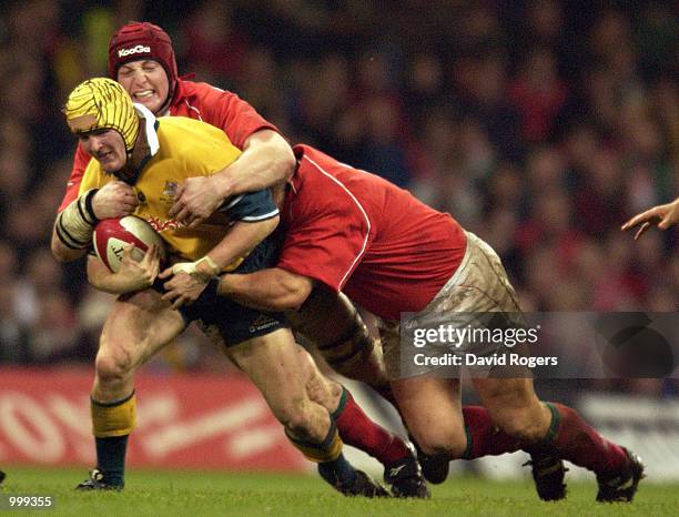 Elton Flatley of Australia is stopped by Ian Gough and Spencer John of Wales during the match between Wales and Australia at the Millennium Stadium,...