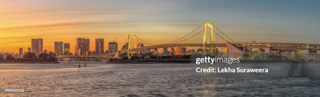 Rainbow bridge and Tokyo skyline at sunset.