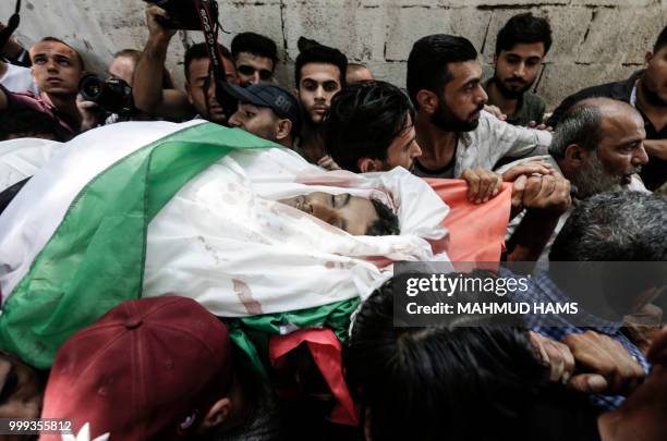 Graphic content / Mourners carry the body of 16-year-old Palestinian Louai Kaheel during his funeral in Gaza City on July 15 after he was killed the...