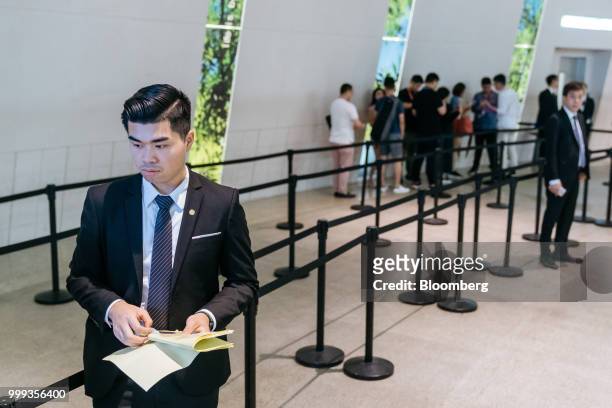 Member of staff stands near a queue for the sales office for the Victoria Harbour residential project, developed by Sun Hung Kai Properties Ltd., in...