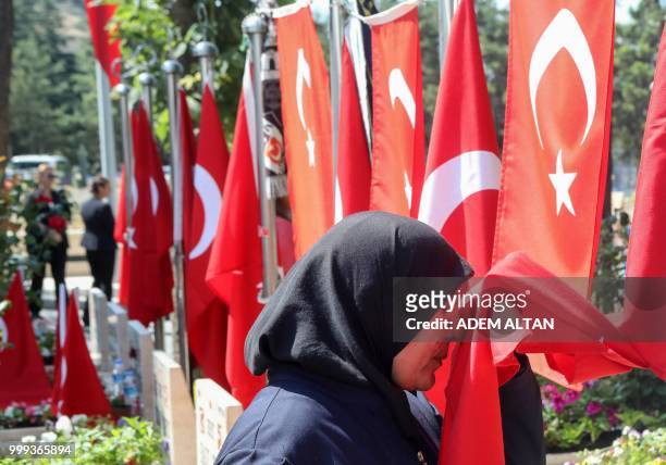 Woman kisses a Turkish flag as people visit graves of their relatives who died during the failed coup in Turkey on July 15 during a ceremony marking...