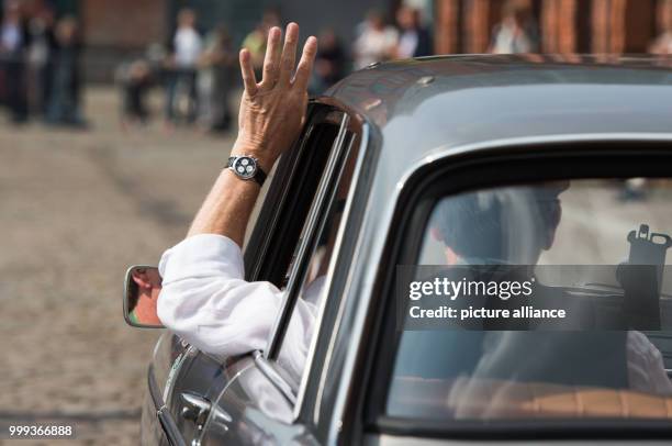 Klaus Ziegner waves his hand to the fans out of his Peugeot 404 Super Luxe, built in 1964, at the start of the Hamburg-Berlin Vintage Car Rallye in...