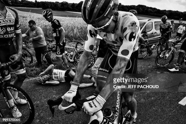 Australia's Simon Clarke lies on the route as Latvia's Toms Skujins , wearing the best climber's polka dot jersey, gets going again after they were...