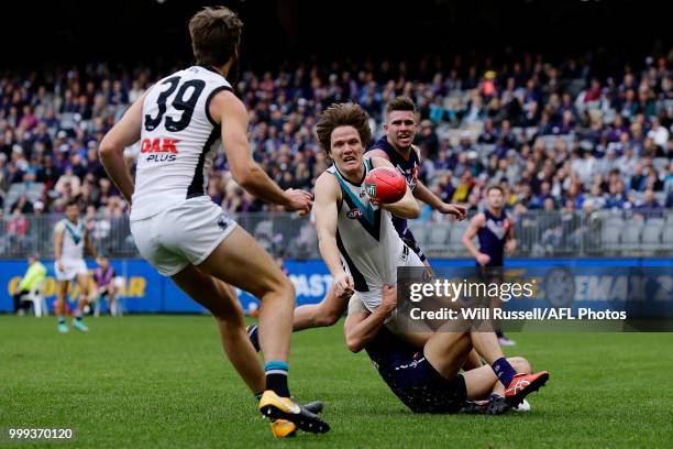 Jared Polec of the Power handpasses the ball under pressure from Adam Cerra of the Dockers during the round 17 AFL match between the Fremantle...