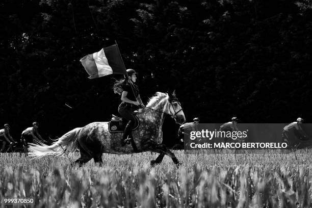 Spectator on horseback waves a French flag as the pack rides during the eighth stage of the 105th edition of the Tour de France cycling race between...