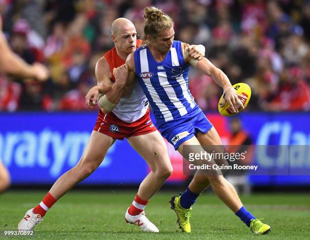 Jed Anderson of the Kangaroos kicks whilst being tackled by Zak Jones of the Swans during the round 17 AFL match between the North Melbourne...