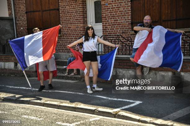 Spectators waving French flags cheer from the side of the route at the start of the ninth stage of the 105th edition of the Tour de France cycling...