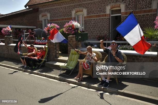 Spectators waving French flags cheer from the side of the route at the start of the ninth stage of the 105th edition of the Tour de France cycling...