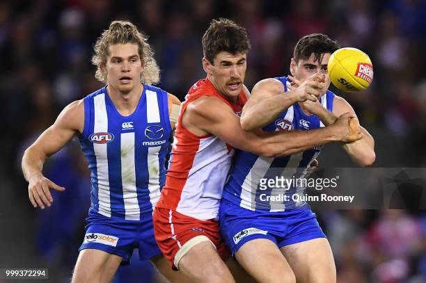 Paul Ahern of the Kangaroos handballs whilst being tackled during the round 17 AFL match between the North Melbourne Kangaroos and the Sydney Swans...
